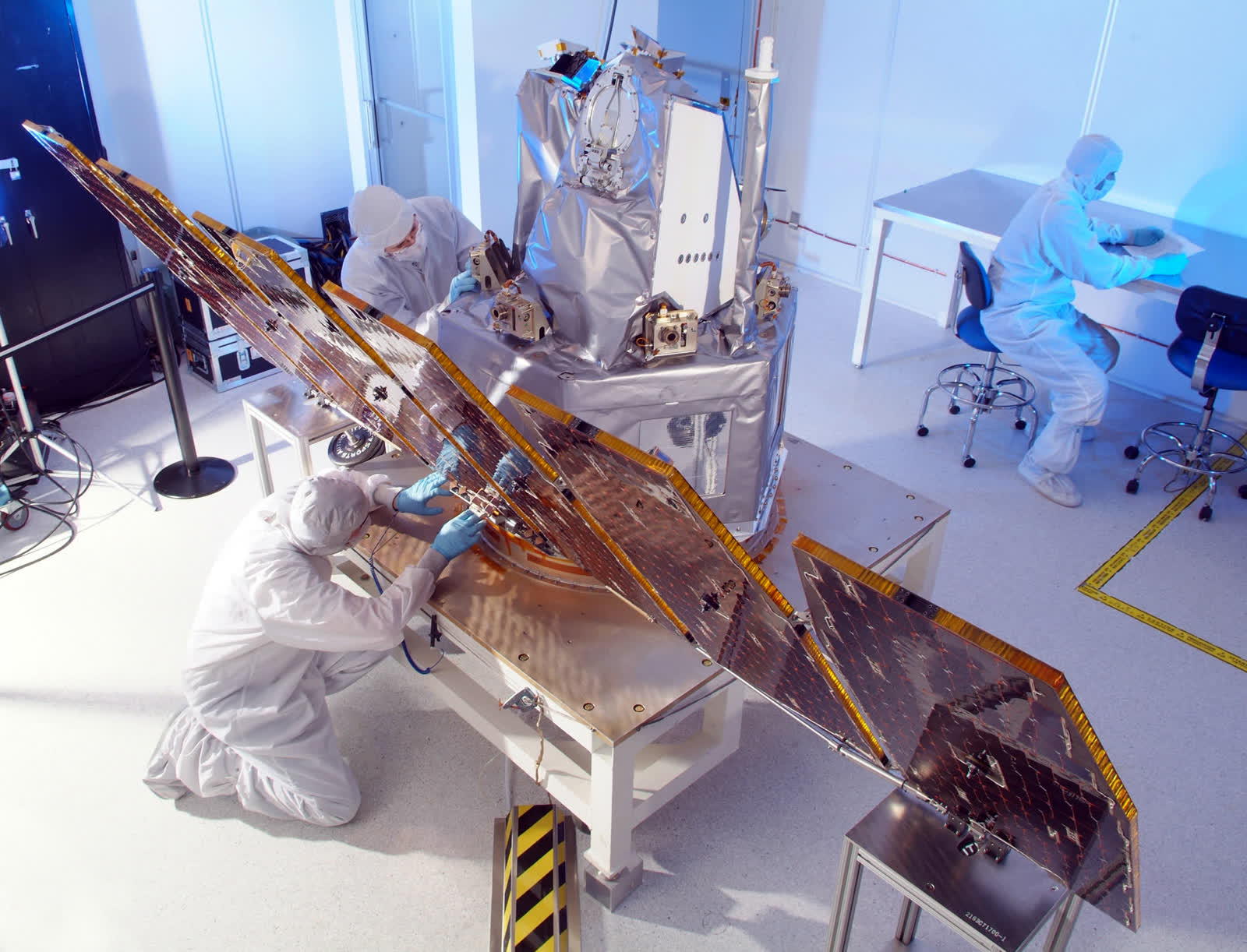 Technicians in protective suits assembling a precision instrument
