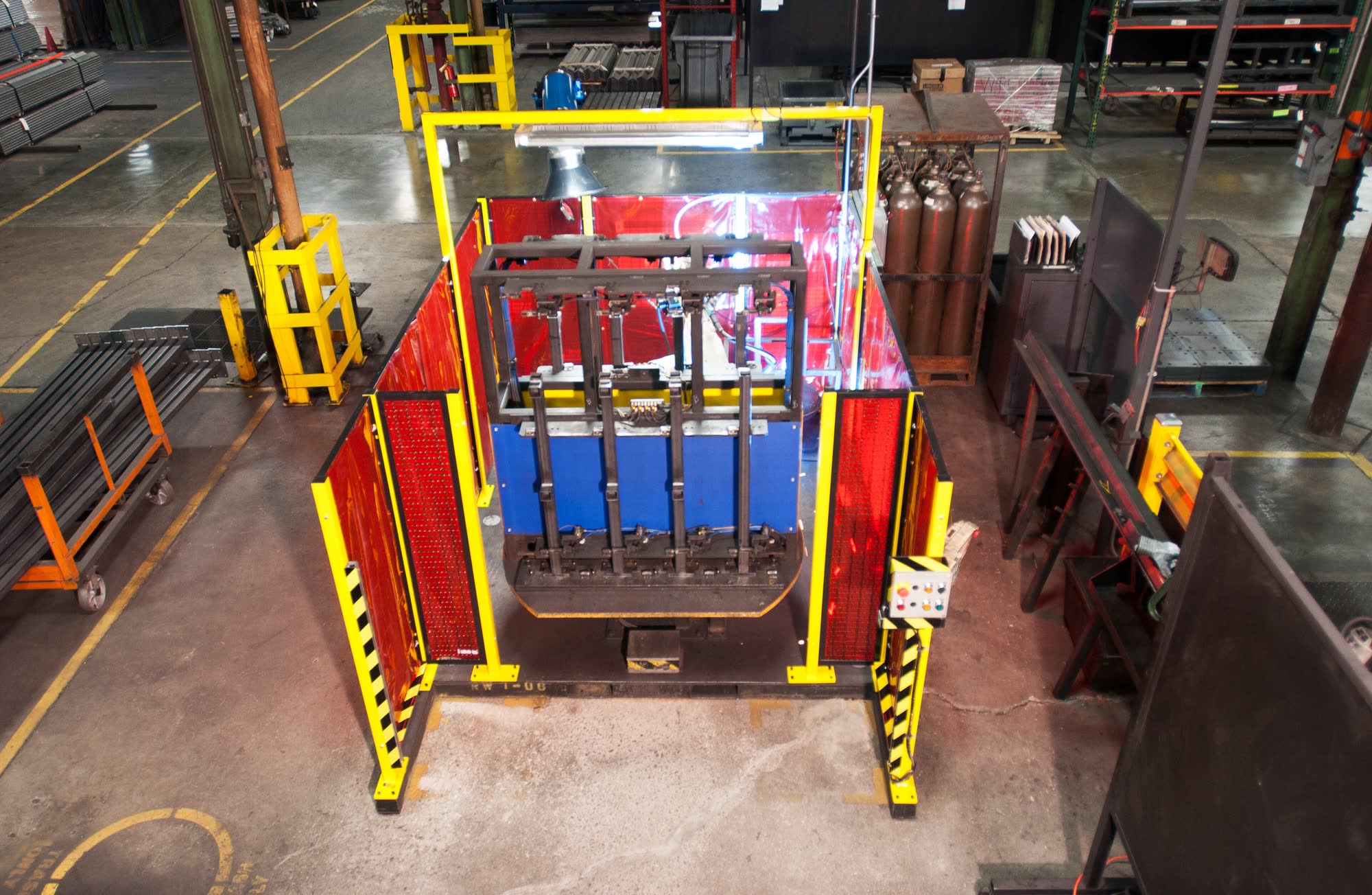 Robotic welding cell with yellow safety guarding on a factory floor